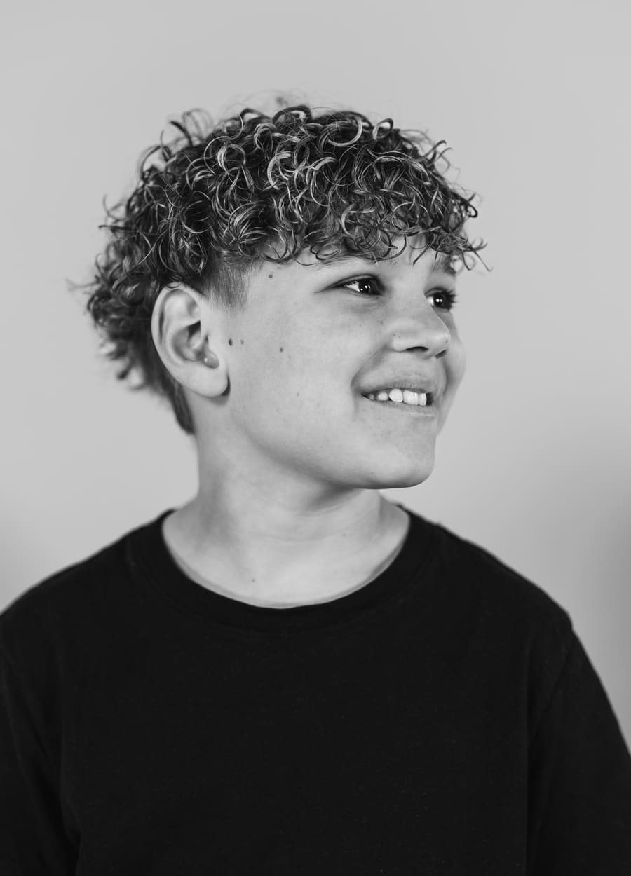 Schulfotografie: Schwarz-Weiß-Portrait eines lächelnden Jungen mit Locken