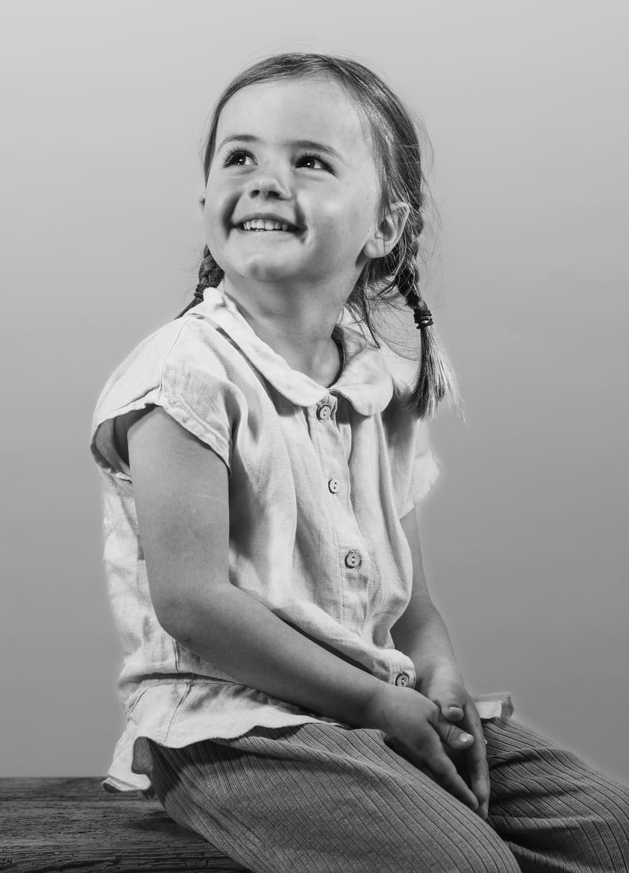 Kindergartenfotografie: Schwarz-Weiß-Portrait eines lachenden Mädchens mit Zöpfen